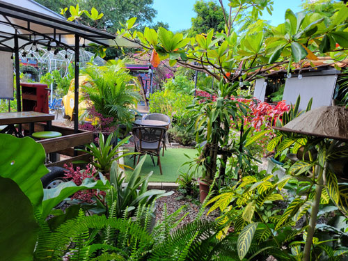 A restaurant where all of the tables are out in a tropical garden